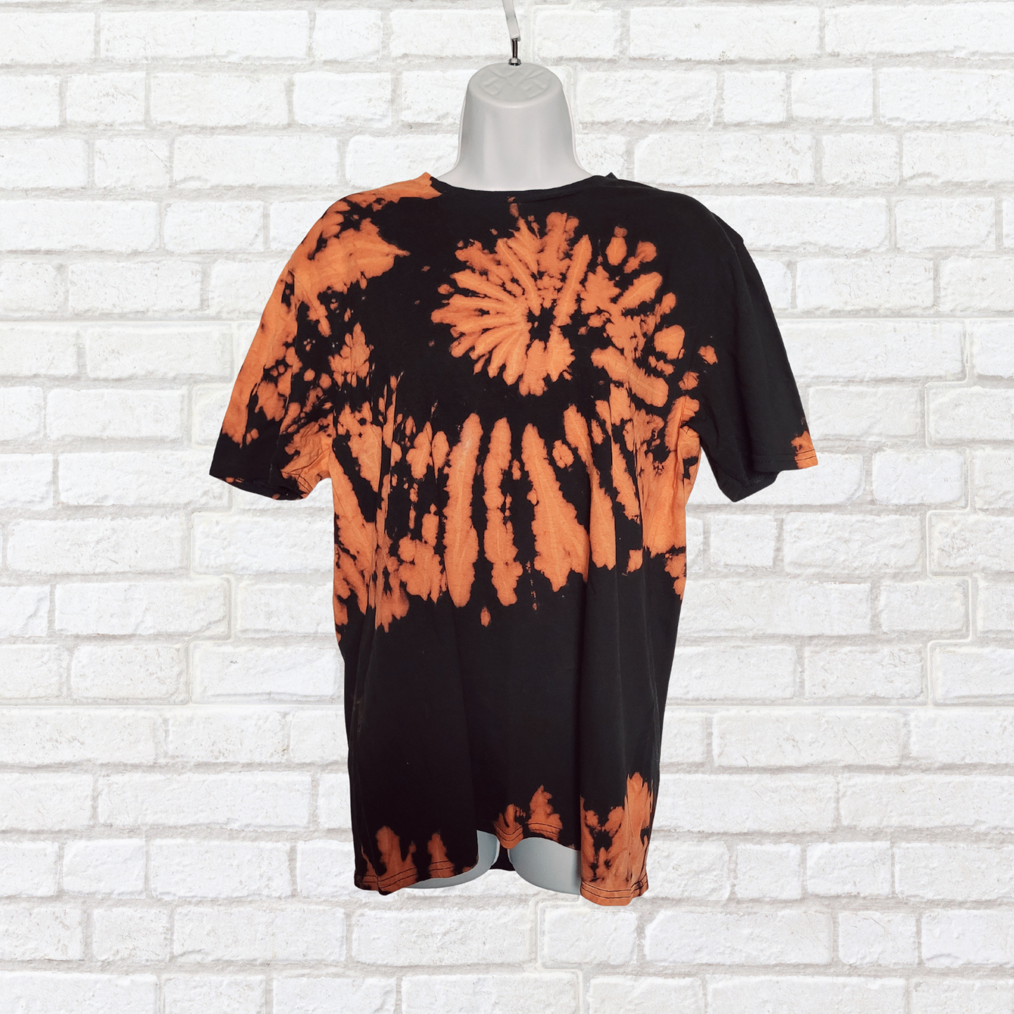 AbiDashery black and orange tie-dye t-shirt on a mannequin against a white wall — Sacral Chakra Collection
